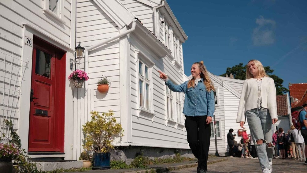 A white building with a red door, numbered 76, and a person pointing at it. 2