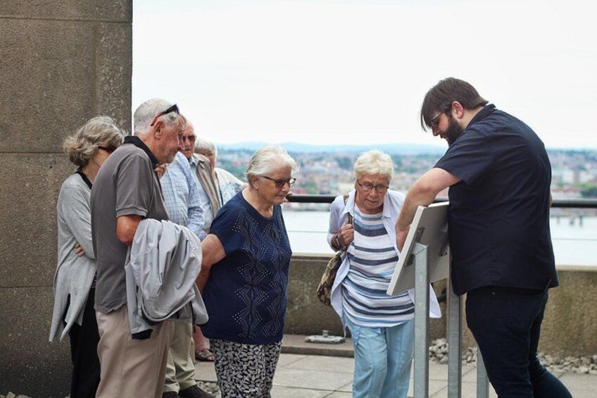 A group of people standing by a railing overlooking a body of water. 4