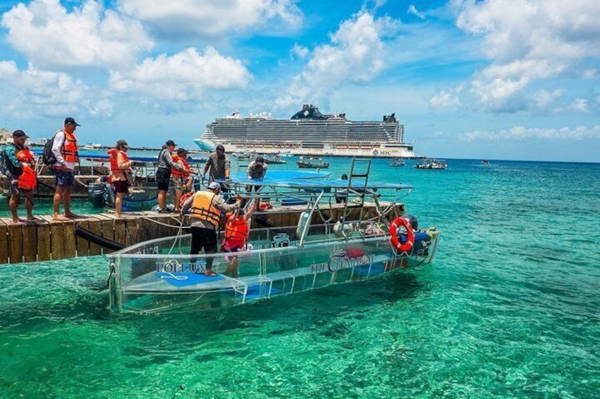 A clear turquoise sea, a cruise ship, and a small boat with people wearing life jackets. 1