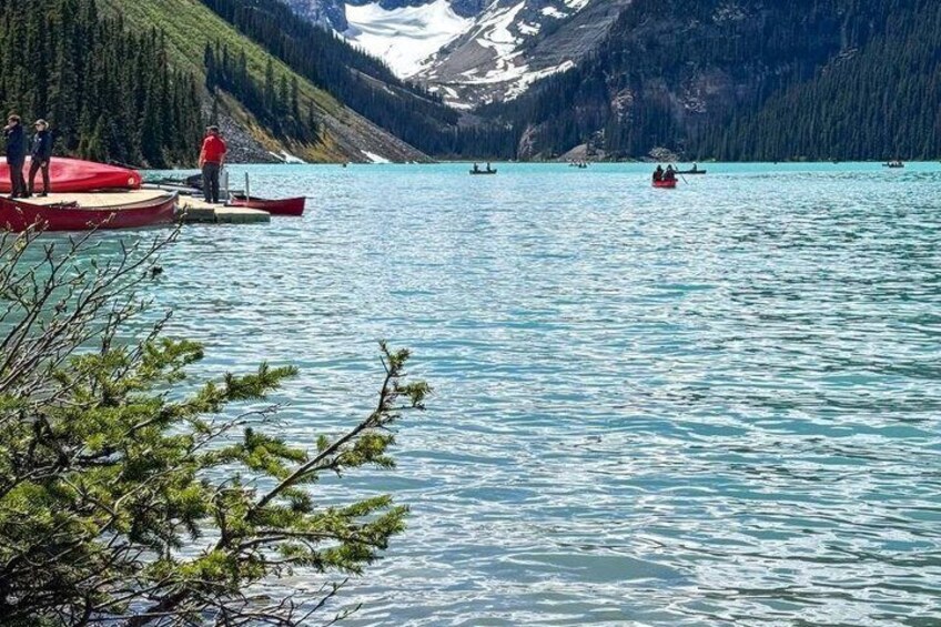 A calm lake with boats, a dock, and a mountainous backdrop. 3