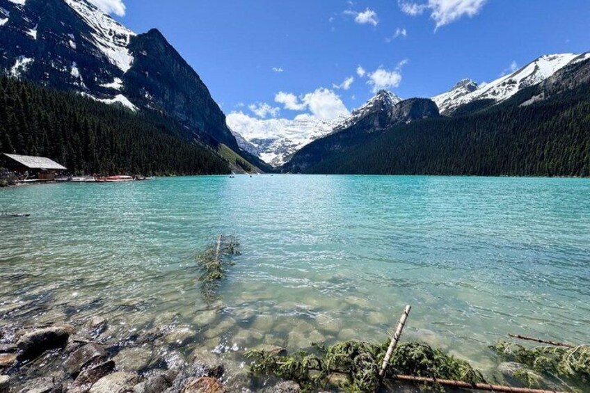 A clear mountain lake with visible underwater rocks and a forested mountain backdrop. 2