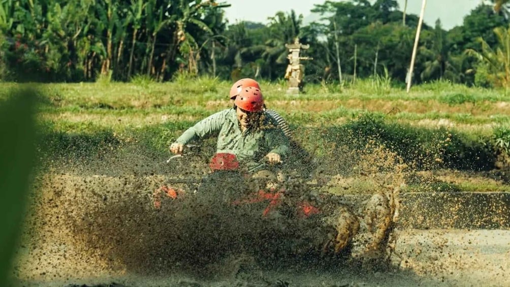 A person riding a motorcycle in a rural area with fields and trees in the background. 5