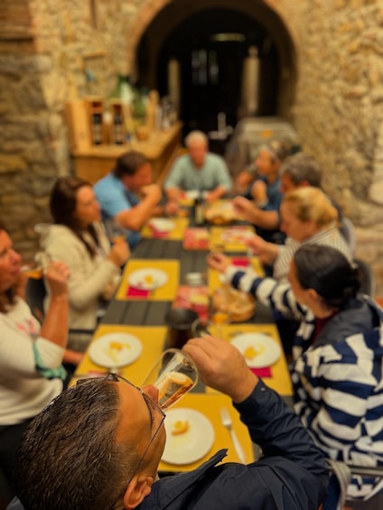 A group of people dining at a long table in a stone-walled room. 1