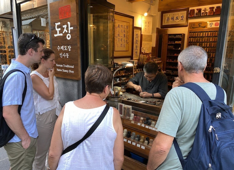 A traditional Korean stamp shop with customers and a craftsman working. 4