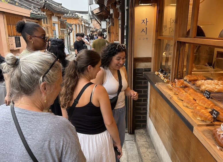 A group of people browsing pastries at a bakery with traditional Korean architecture. 3