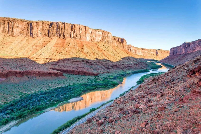 A canyon with a river reflecting the sky, surrounded by rocky terrain and sparse vegetation. 4