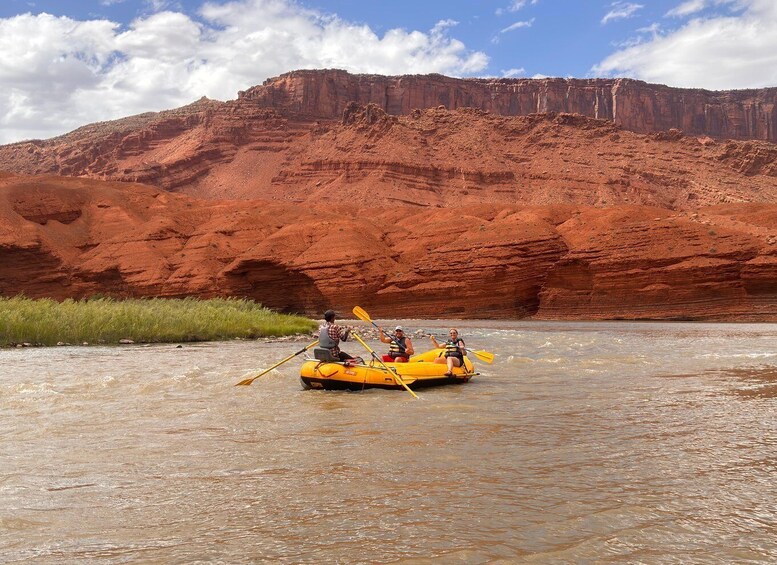 A group of people rafting on a river with red rock cliffs in the background. 1