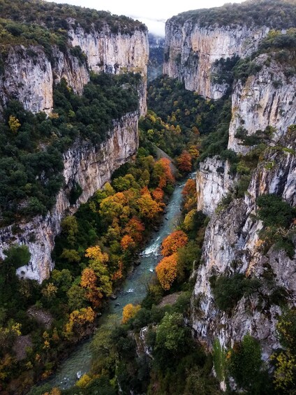 A canyon with a river, surrounded by cliffs and autumn-colored trees. 1