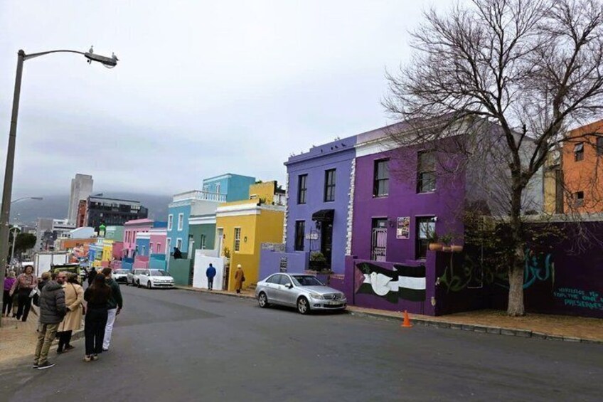 A street with colorful buildings, a tree, and a parked car. 2