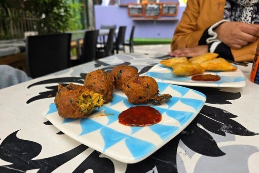 A table with food, including fritters and a plate with a red sauce. 4