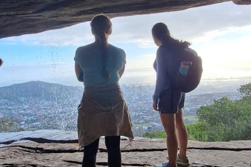 Two people standing on a rocky outcrop overlooking a cityscape. 3