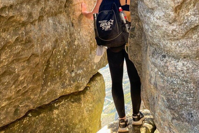 A person hiking through a narrow rocky passage. 4