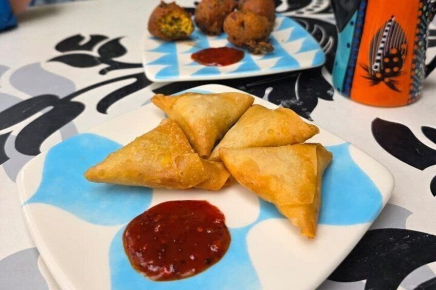 A plate of samosas with a side of chutney. 5