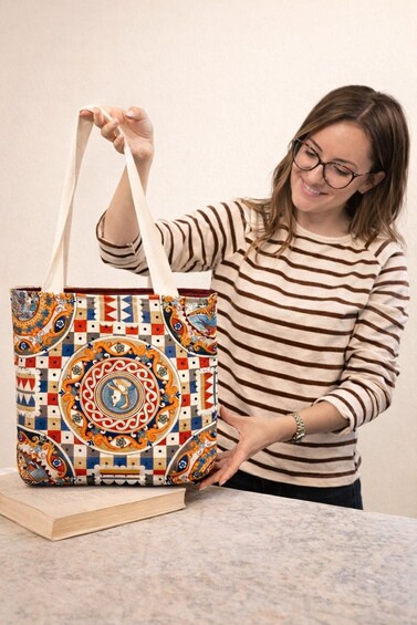 A person holding a patterned tote bag with a circular design. 4