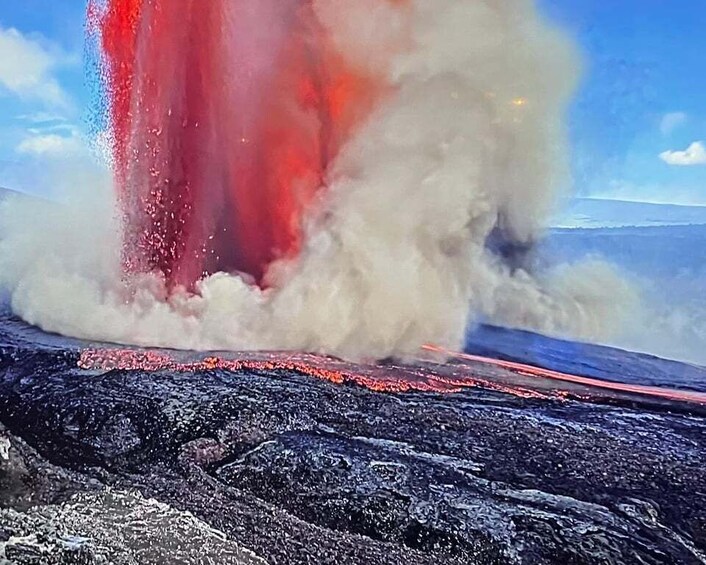 A volcanic eruption with lava flowing and a large plume of ash and smoke. 1