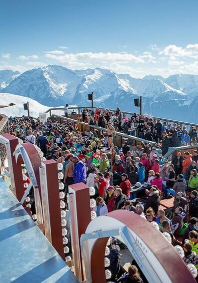 A crowded outdoor event with a mountainous backdrop. 1