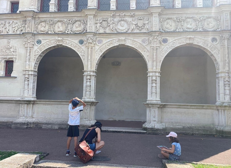 A group of people near a building with ornate arches and detailed carvings. 5