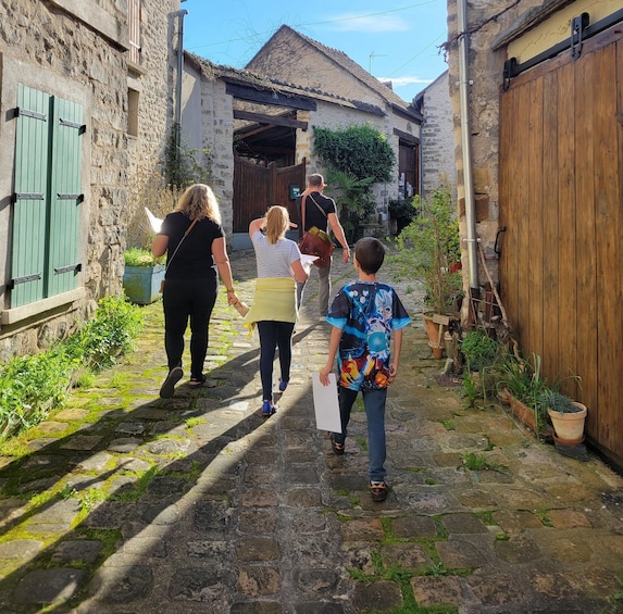 A narrow stone pathway in a rustic village with stone buildings and wooden shutters. 1