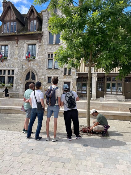 A group of people standing in front of a historic stone building with a tree in the foreground. 2