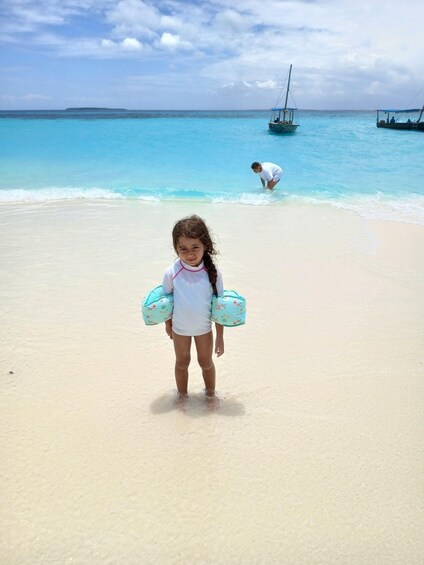 A child on a beach with a boat in the background. 3