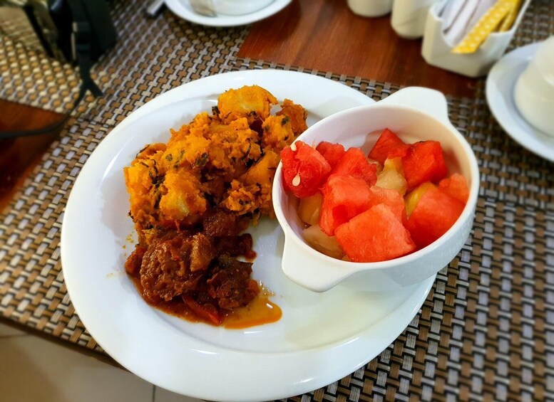 A plate of food with mashed potatoes and a bowl of diced watermelon. 2