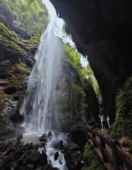 A waterfall cascading down a rocky cliff surrounded by lush greenery. 1