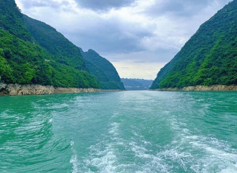 A river flanked by lush green hills under a cloudy sky. 2
