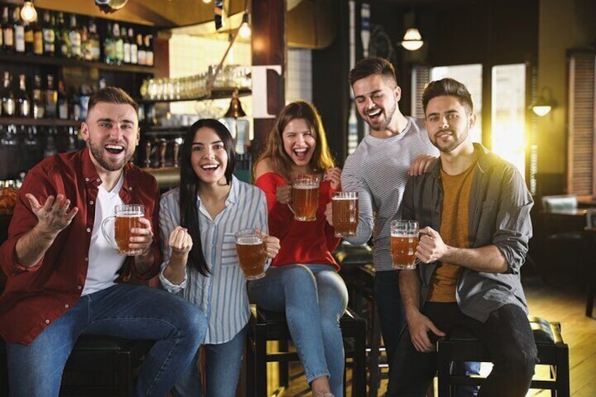 Een groep mensen zit aan een bar met bierglazen. 1