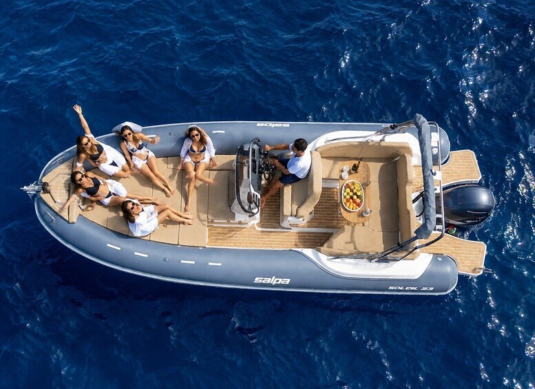 A small motorboat with a group of people on board, floating on blue water. 1