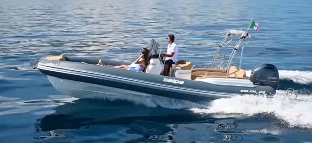 A motorboat with two people on board, one steering and one sitting, moving through calm water. 2