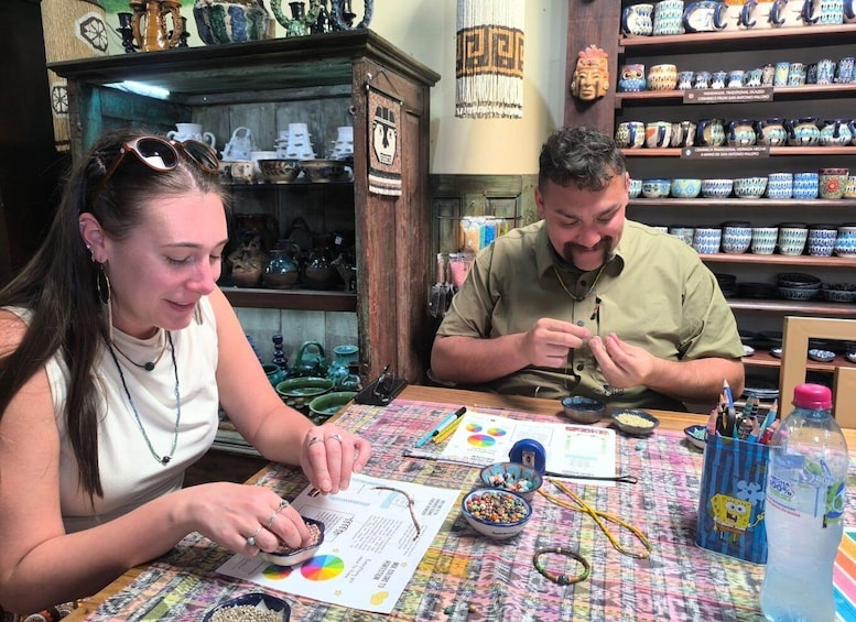 Two people at a table with ceramic items and a colorful tablecloth. 3