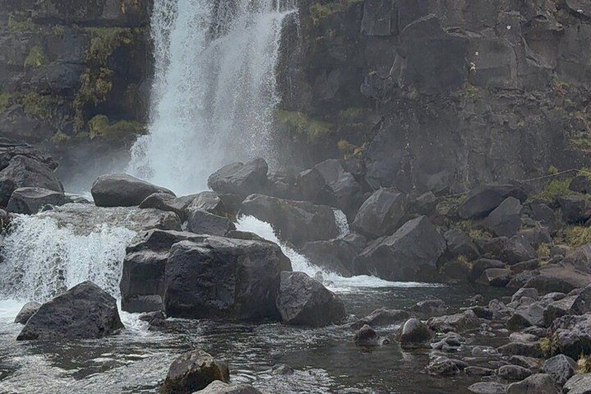 A waterfall cascading over rocks into a river, surrounded by a rocky landscape. 4