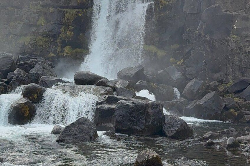 A waterfall cascading over rocks in a forested area. 5