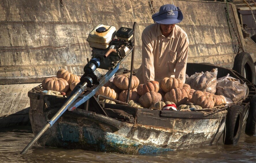 A man in a boat filled with pumpkins and a motor. 1