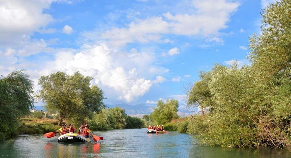 Two groups of people rafting on a river surrounded by greenery. 2