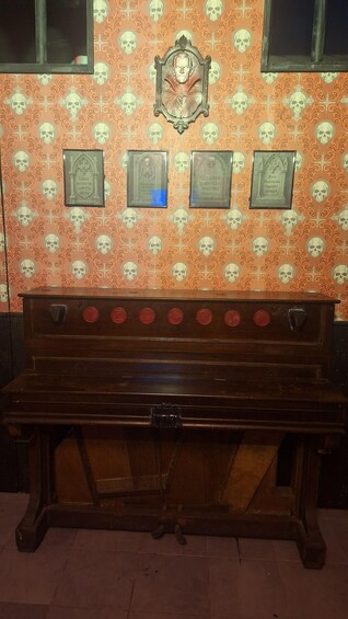 A wooden bench with a skull and crossbones design, against a wall with skull patterns and plaques. 3