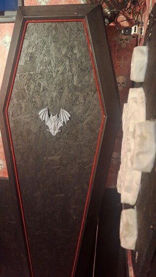 A coffin-shaped object with a bat emblem, surrounded by red and black striped tape. 4