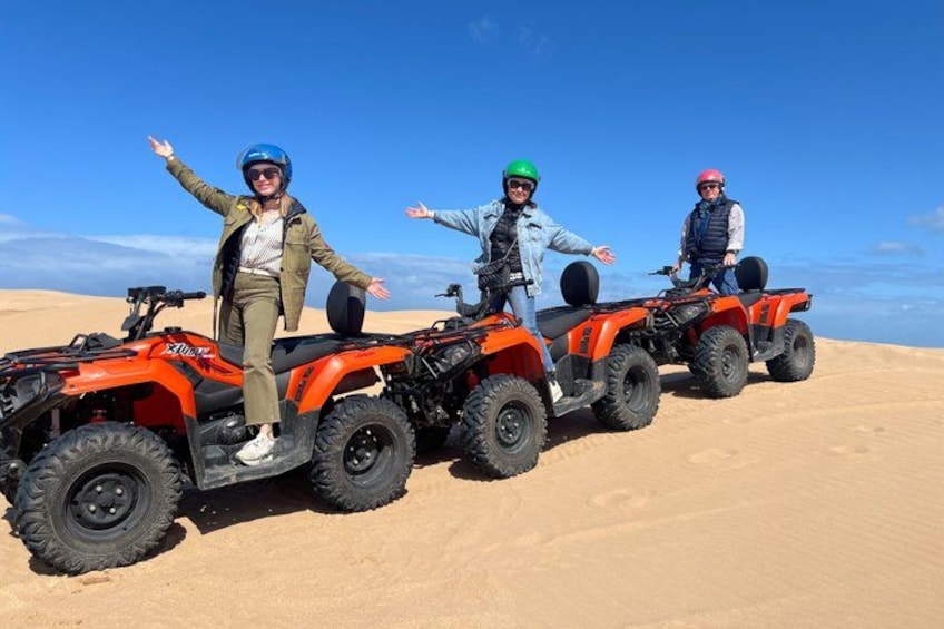 Drei Personen fahren mit Quads durch eine Wüste mit Sanddünen. 4