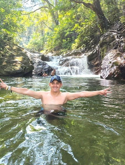 A person in a forested area with a waterfall in the background. 4