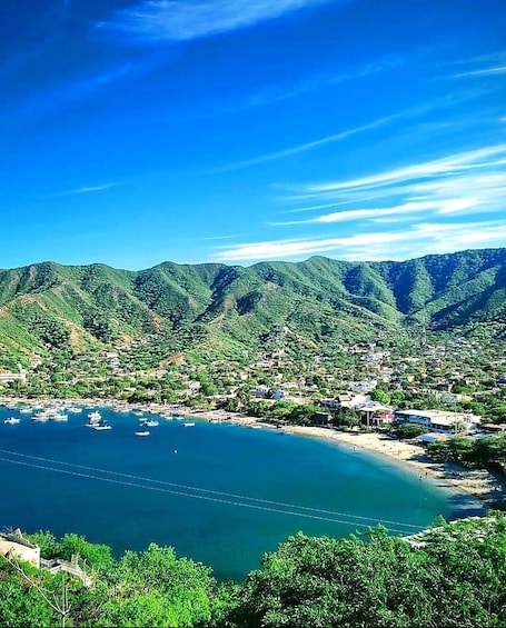 A coastal town with mountains in the background and boats on the water. 1