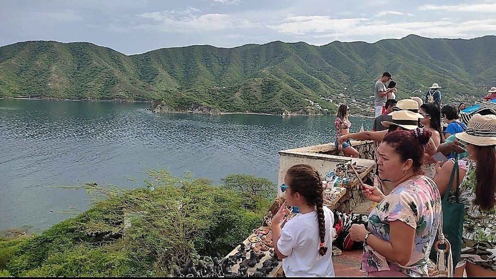A group of people sitting by a lakeside with mountains in the background. 2