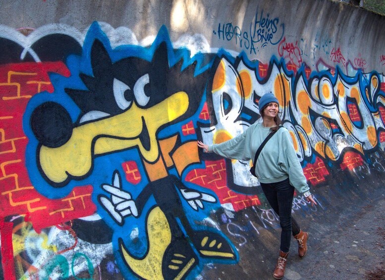 A person standing in front of a colorful graffiti wall with cartoon characters. 3