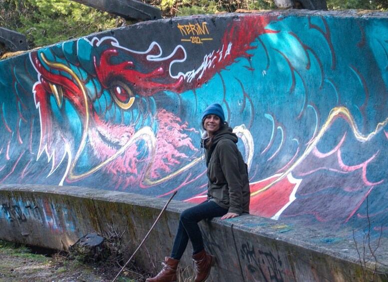 A person sitting on a concrete ledge with colorful graffiti. 5