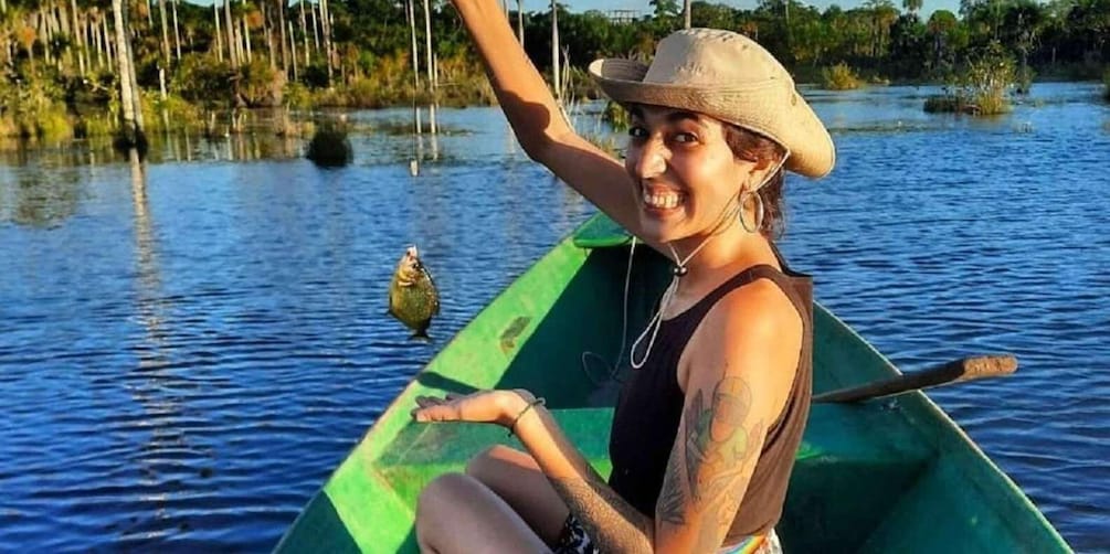 A person in a green canoe on a calm body of water with trees in the background. 1