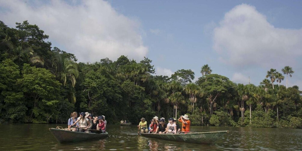 Two boats with people on a river surrounded by dense tropical foliage. 5