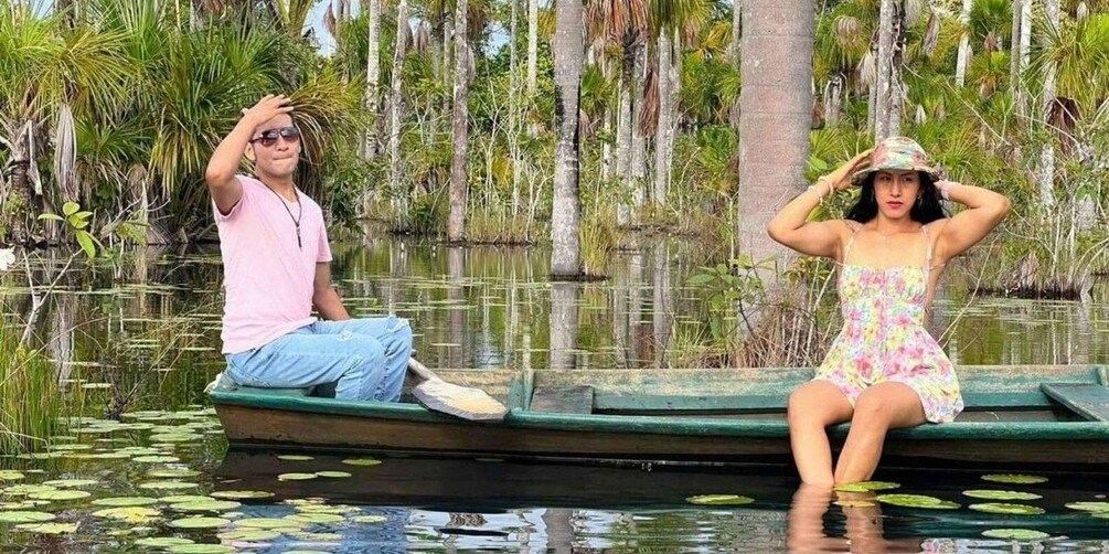 Two people sitting on a boat in a water body surrounded by trees. 2