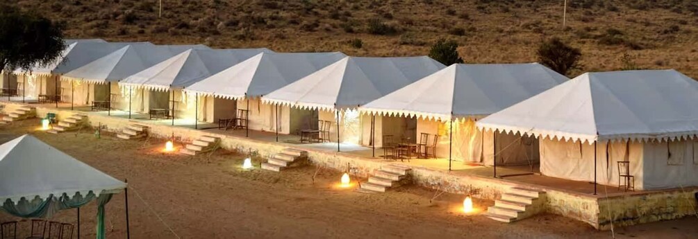 A row of white tents with steps leading to the entrance, set in a desert landscape. 1