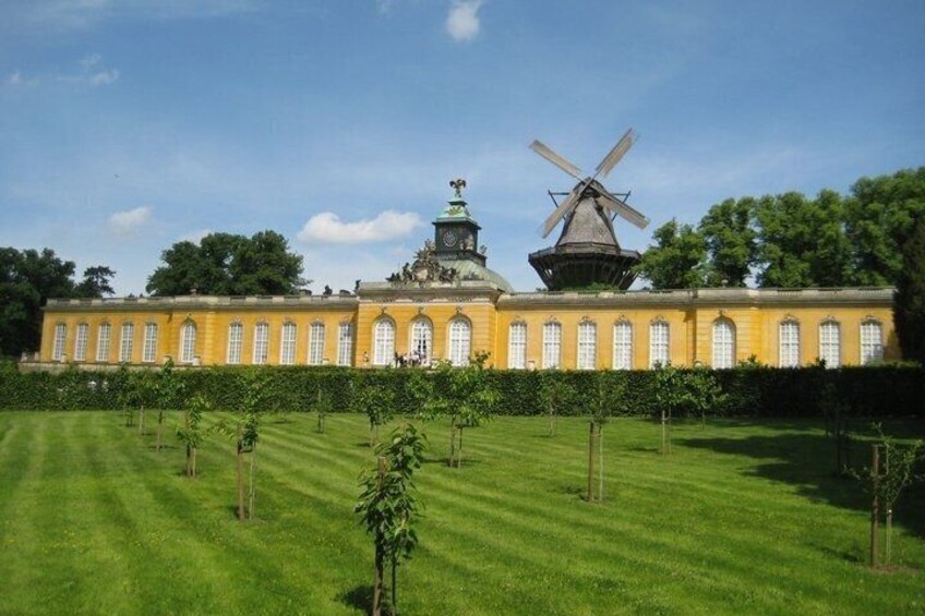 A yellow building with a windmill, surrounded by a well-manicured lawn and trees. 5