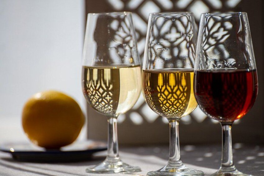 Tre vinglas med olika färgade vätskor, en citron och en mönstrad bakgrund. 1