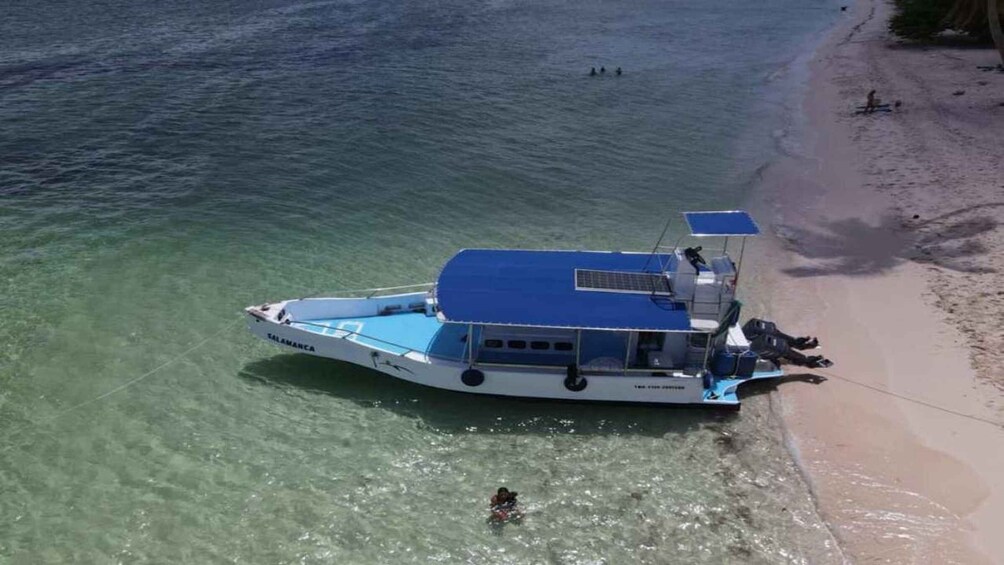 A boat named 'SALAMANC' anchored near a beach with clear water. 3